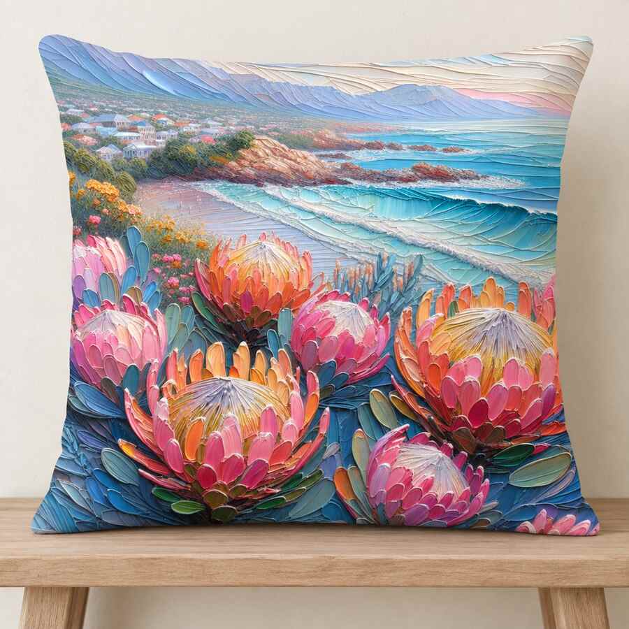 Coastal Protea 45 × 45 cm cotton scatter cushion displayed on a light wooden bench, featuring colourful proteas and a blue coastal scene.
