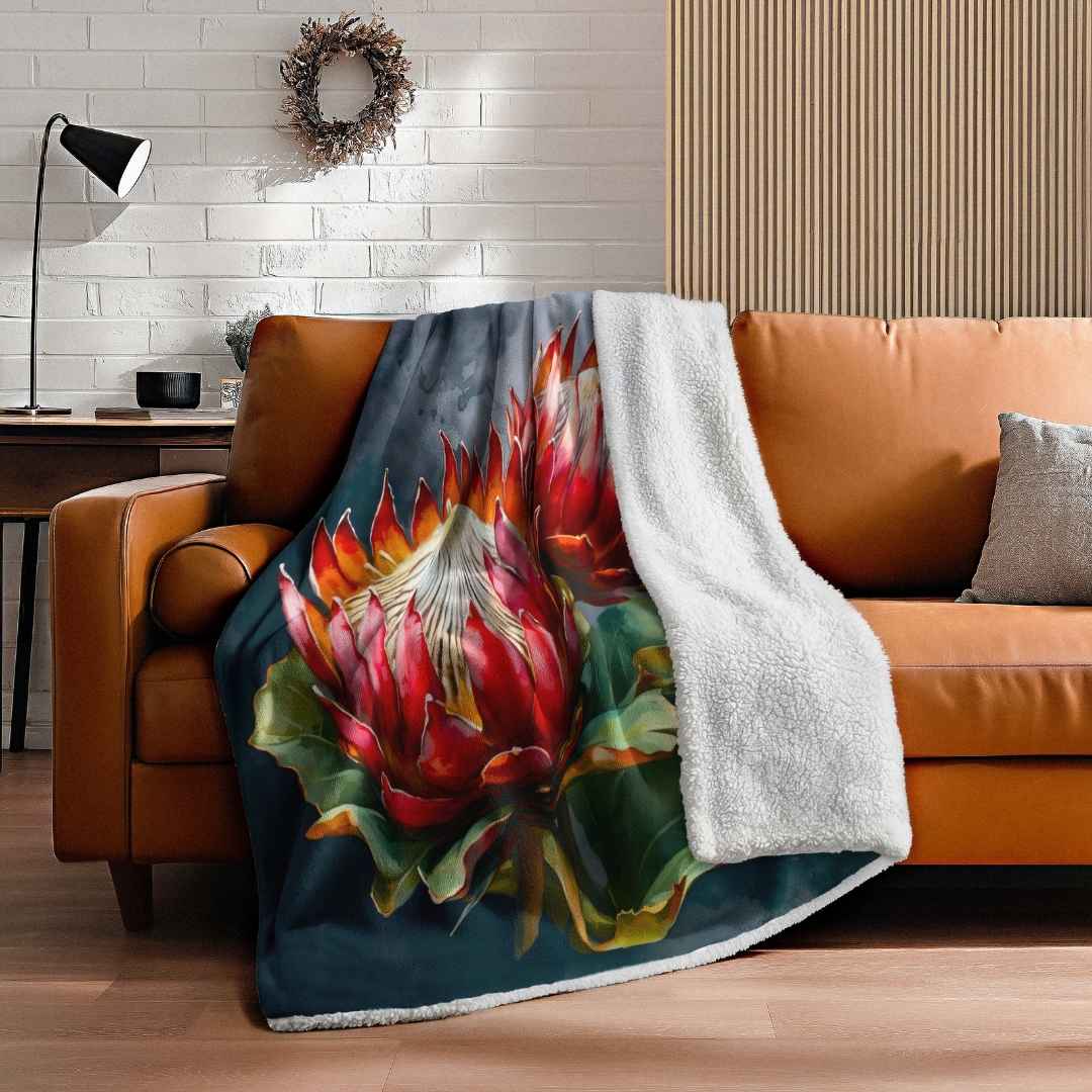 Double layer sheep fleece blanket with bold protea print on a tan leather couch in a South African home