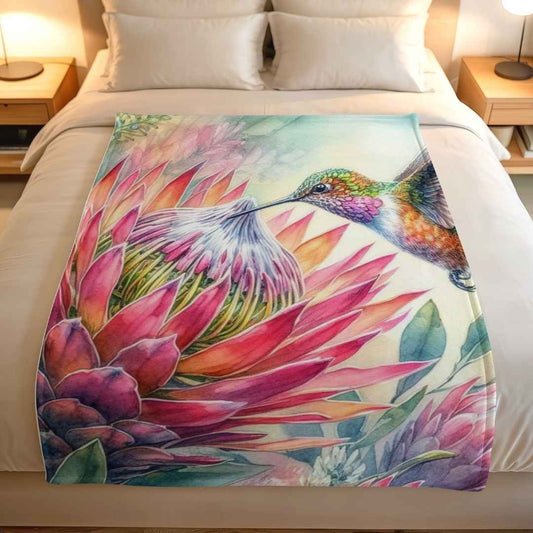 Lightweight fleece blanket with colourful proteas and a hummingbird, displayed on a neutral bed, available online in South Africa.