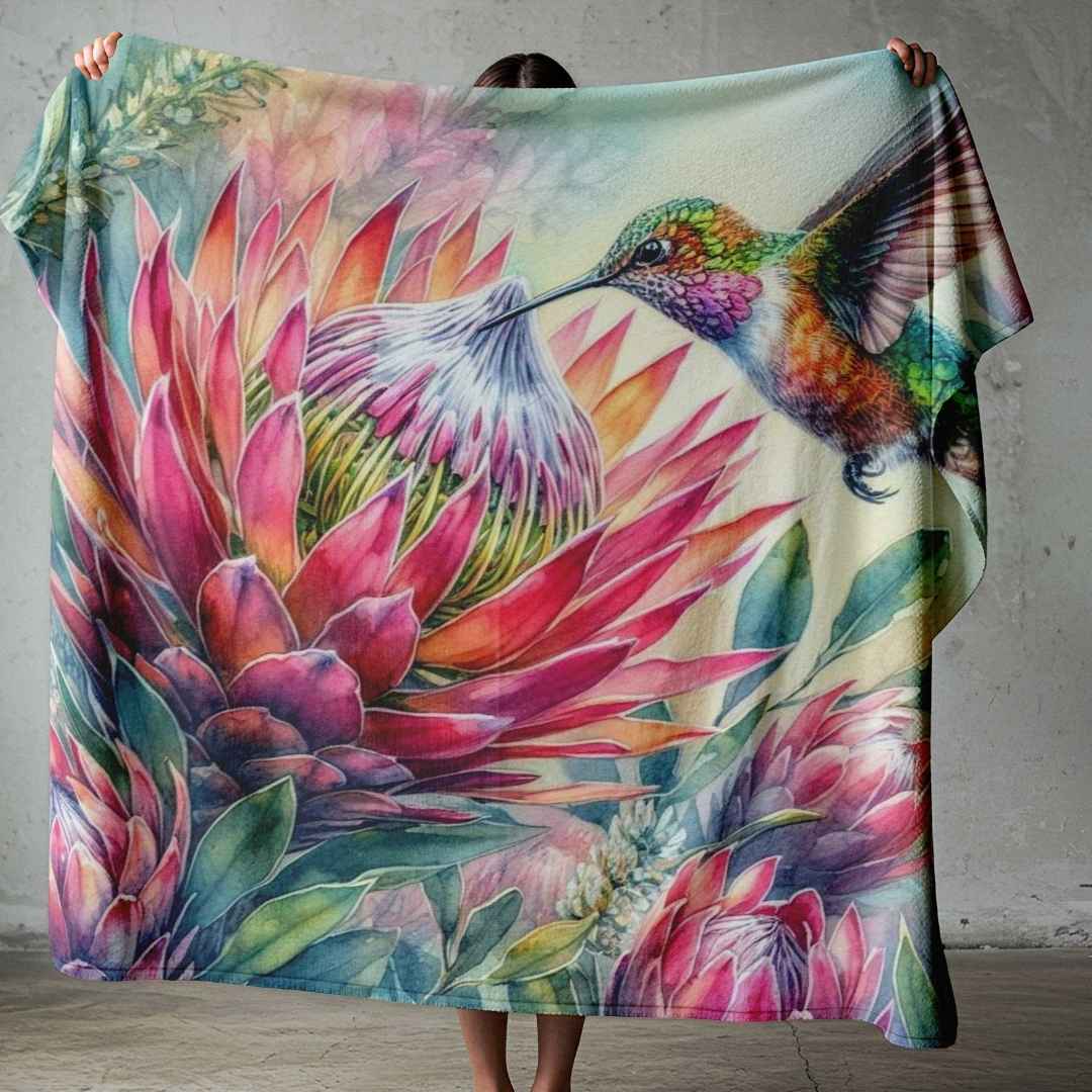 South African lightweight fleece blanket with protea artwork and a colourful hummingbird, styled across the foot of a bed.