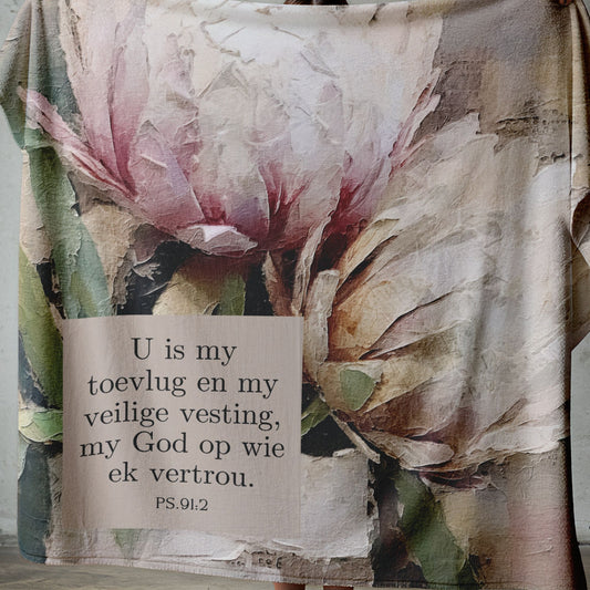 Lightweight coral fleece blanket with vintage-style protea artwork and Psalm 91:2 Scripture in Afrikaans, suitable for home décor, prayer, or gifting.