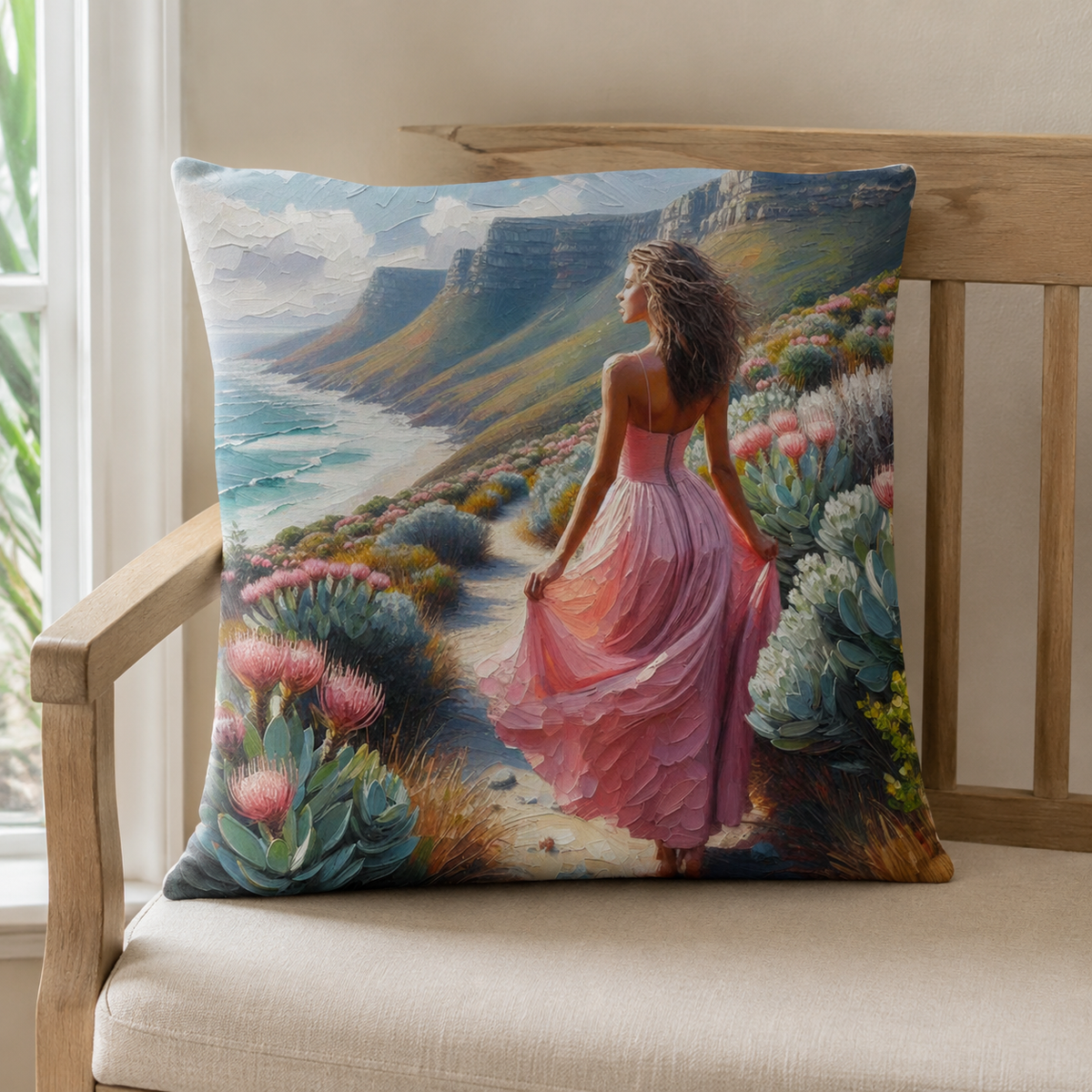 South African-inspired cotton scatter cushion cover with a pink-dress coastal artwork, displayed on a natural wooden bench.
