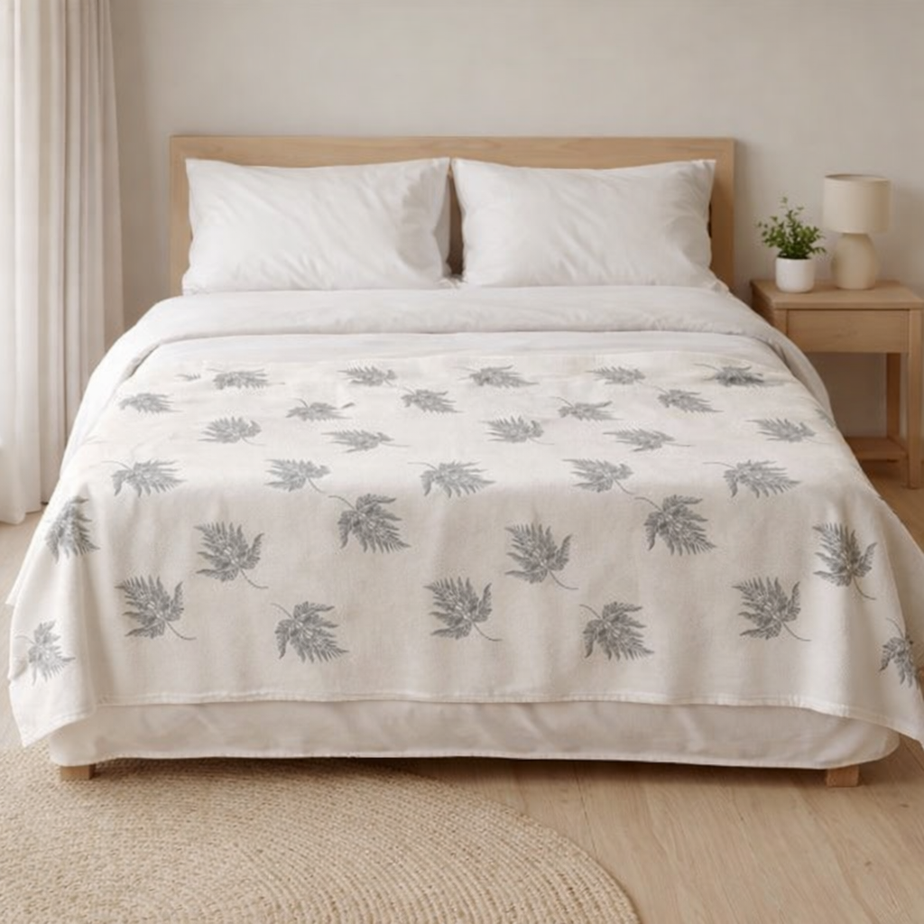 Soft botanical fleece throw blanket placed across white duvet minimalist bedroom décor