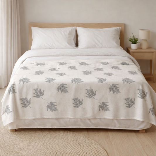 Soft botanical fleece throw blanket placed across white duvet minimalist bedroom décor