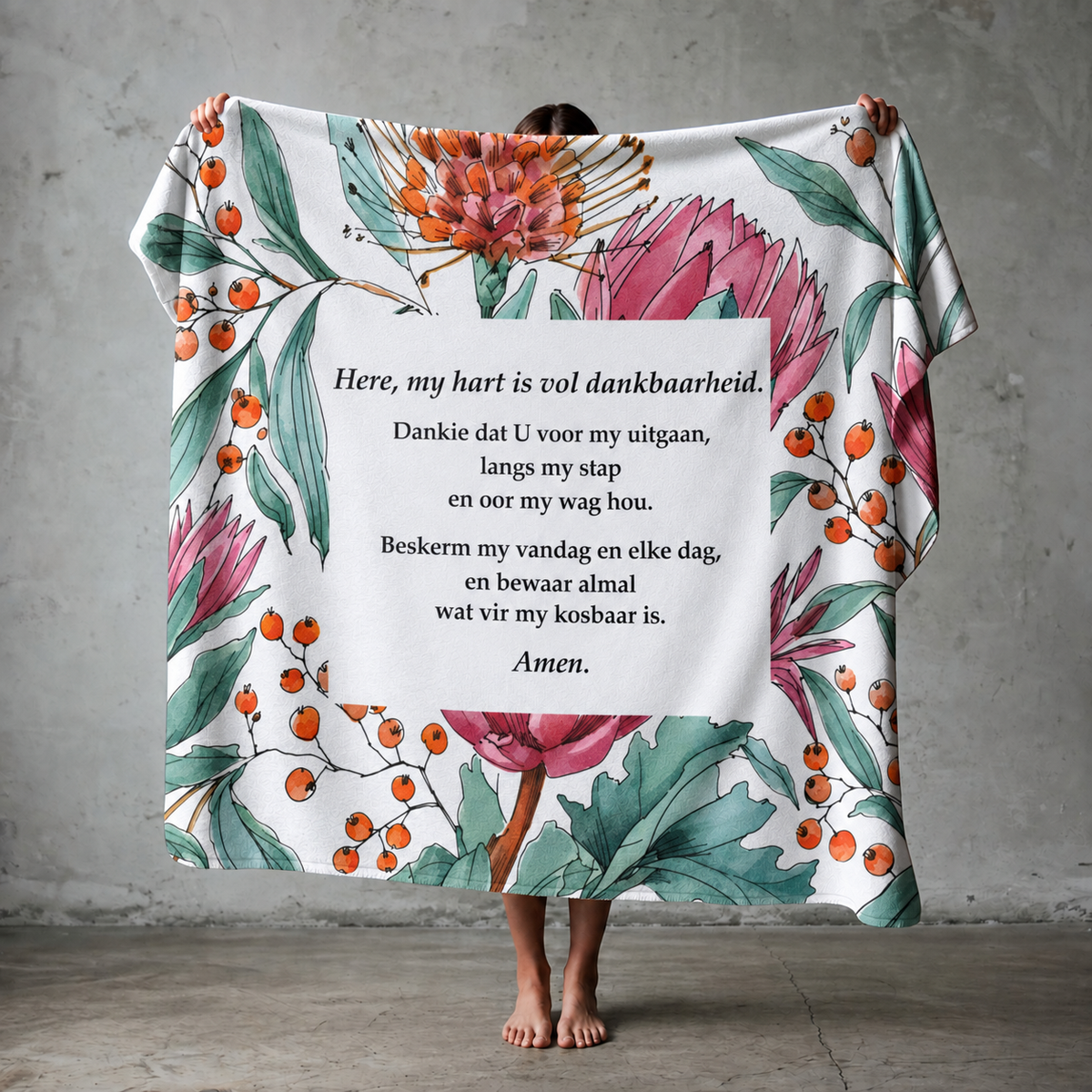 Woman holding a lightweight fleece throw blanket featuring an Afrikaans prayer and colourful protea print