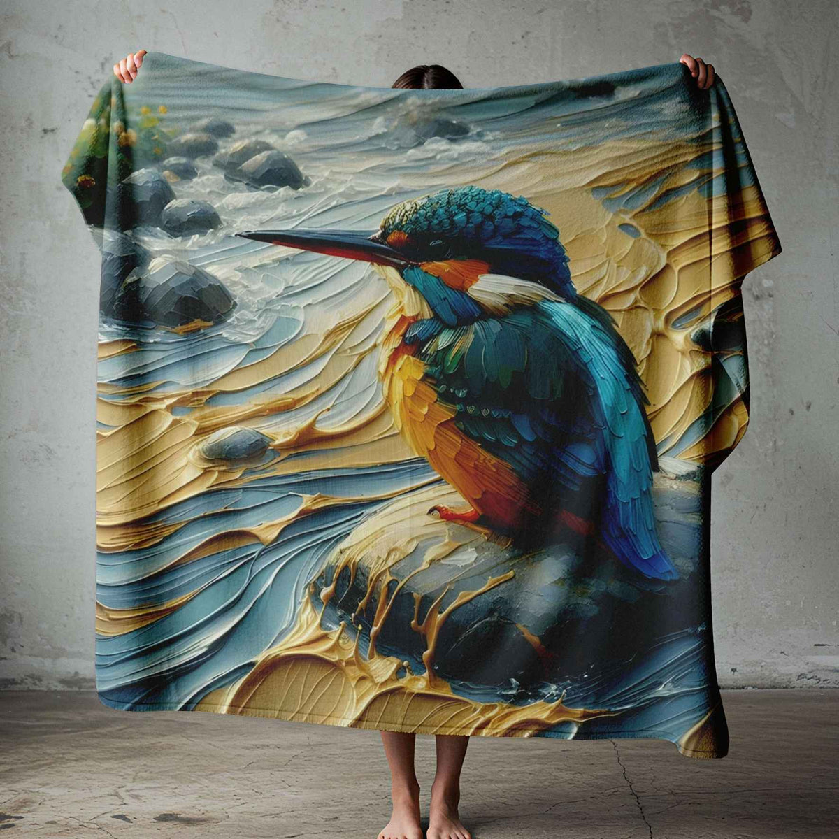 Kingfisher fleece blanket with teal-blue feathers and amber detail against a cream, gold and grey painterly background, displayed on a bed.